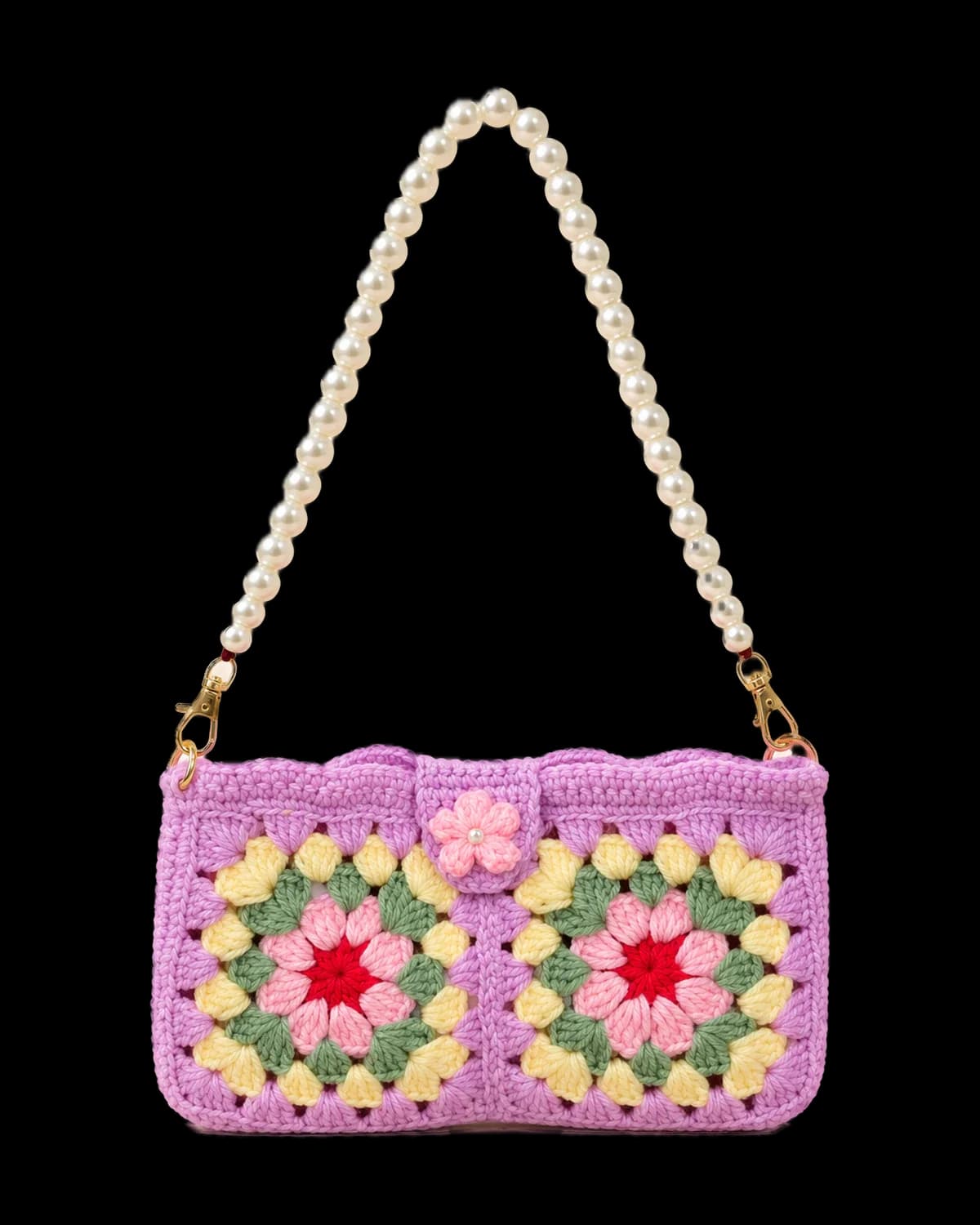 Lilac crochet shoulder bag with two flower granny squares, a pink flower tab closure and a white faux-pearl strap with gold-tone clasps, on a cream background