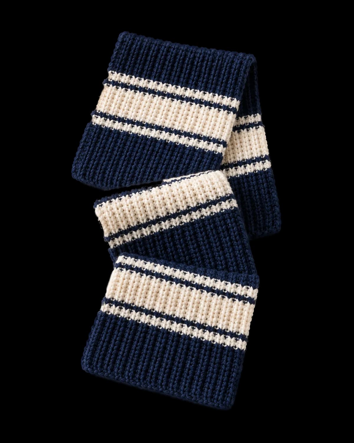 Navy and cream striped ribbed crochet scarf folded in a zigzag on a cream background