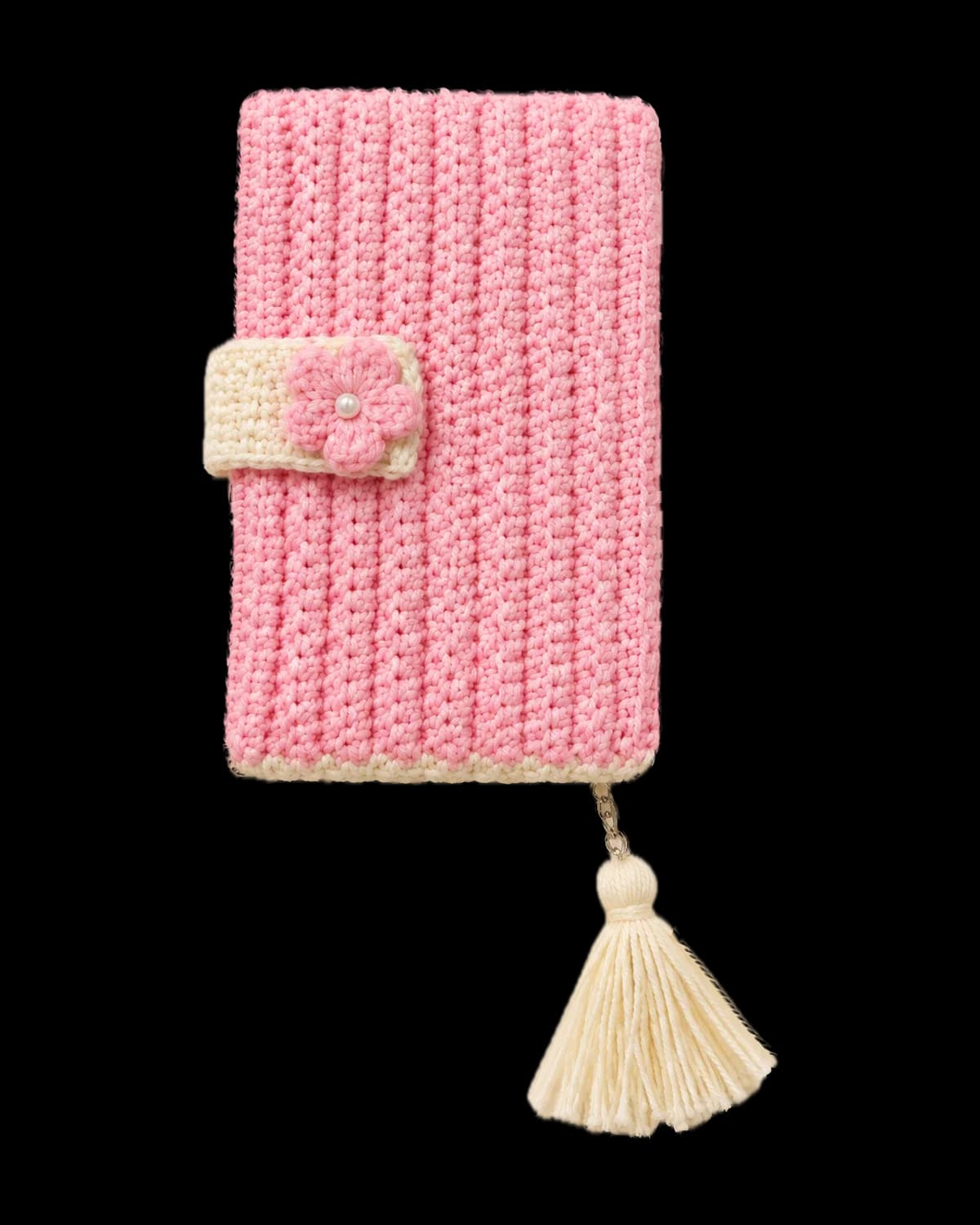Light pink ribbed crochet diary cover with a cream bottom edge, a cream tab closure with a pink pearl-centred flower and a cream tassel on a silver chain, on a cream background