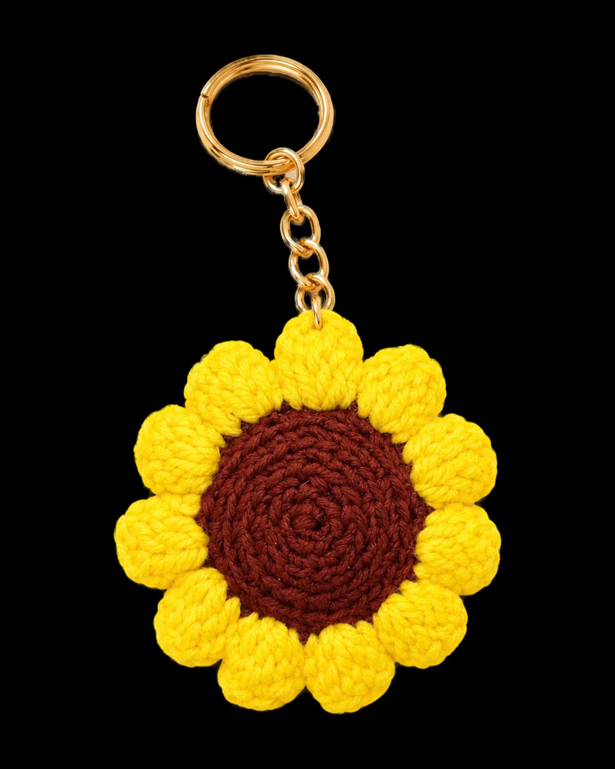 Crochet sunflower keychain with bright yellow puffy petals and a dark brown centre on a gold-tone chain and key ring, on a cream background